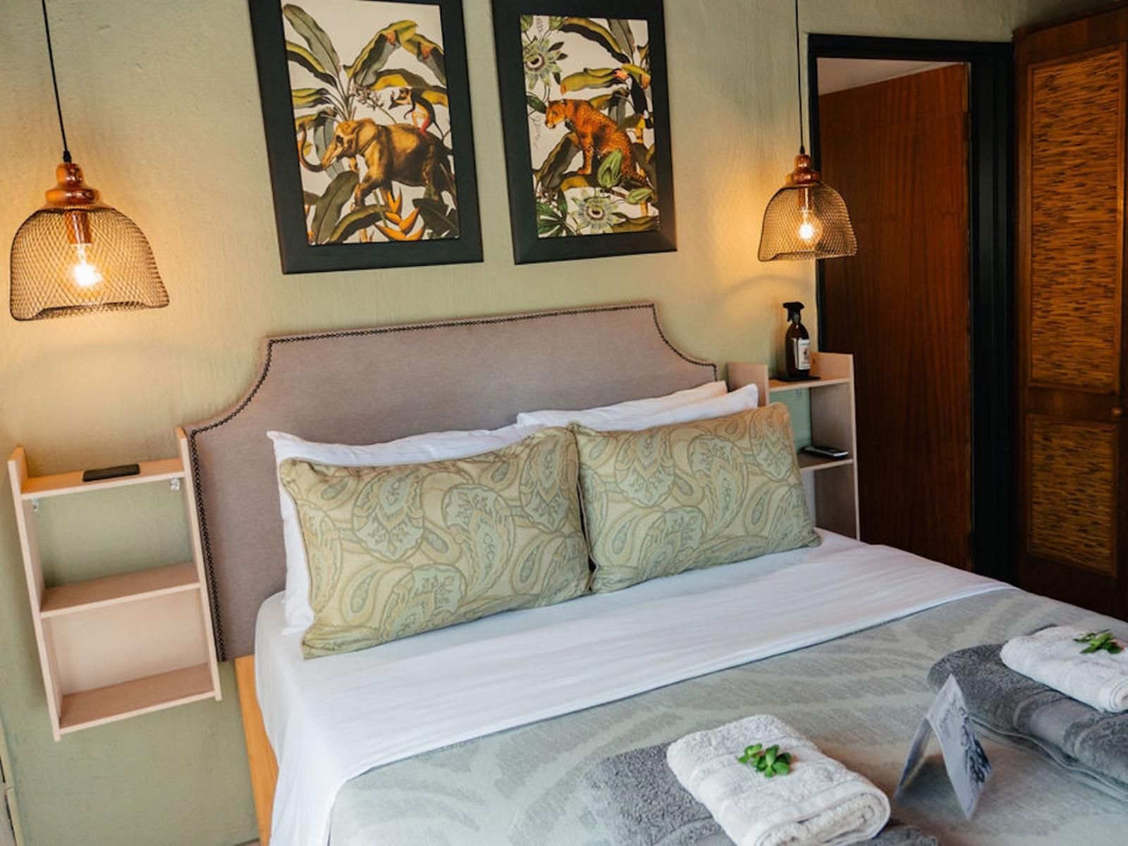 A neatly made bed with two pillows, a bedside table with a bottle, and two wall-mounted lamps.