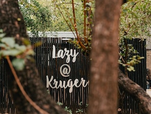 Ein Holzzaun mit einem Schild, auf dem 'Lazy @ Kruger' steht.