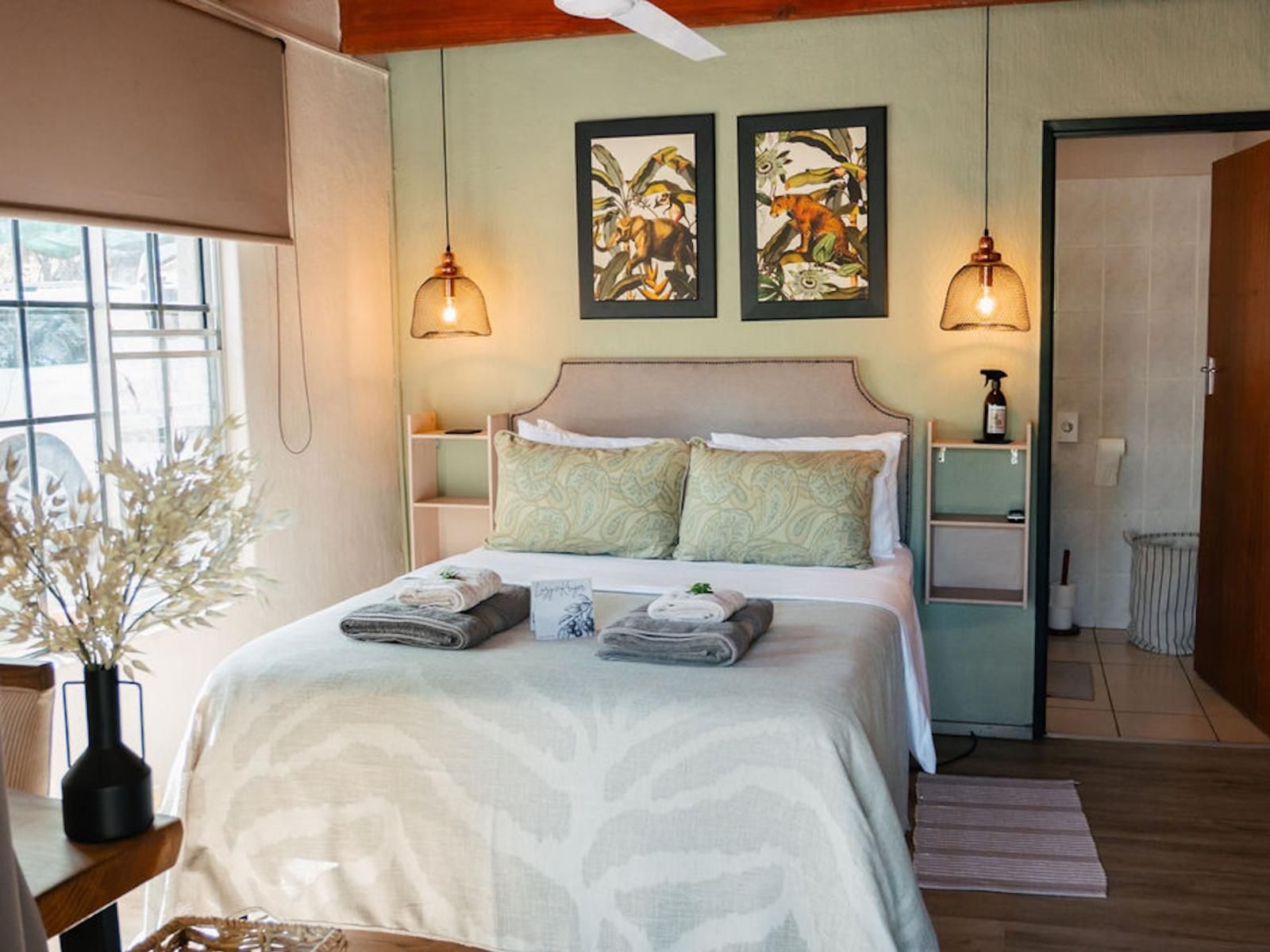 Habitación de hotel con cama, dos lámparas de pared, una ventana y puerta de acceso a un baño.