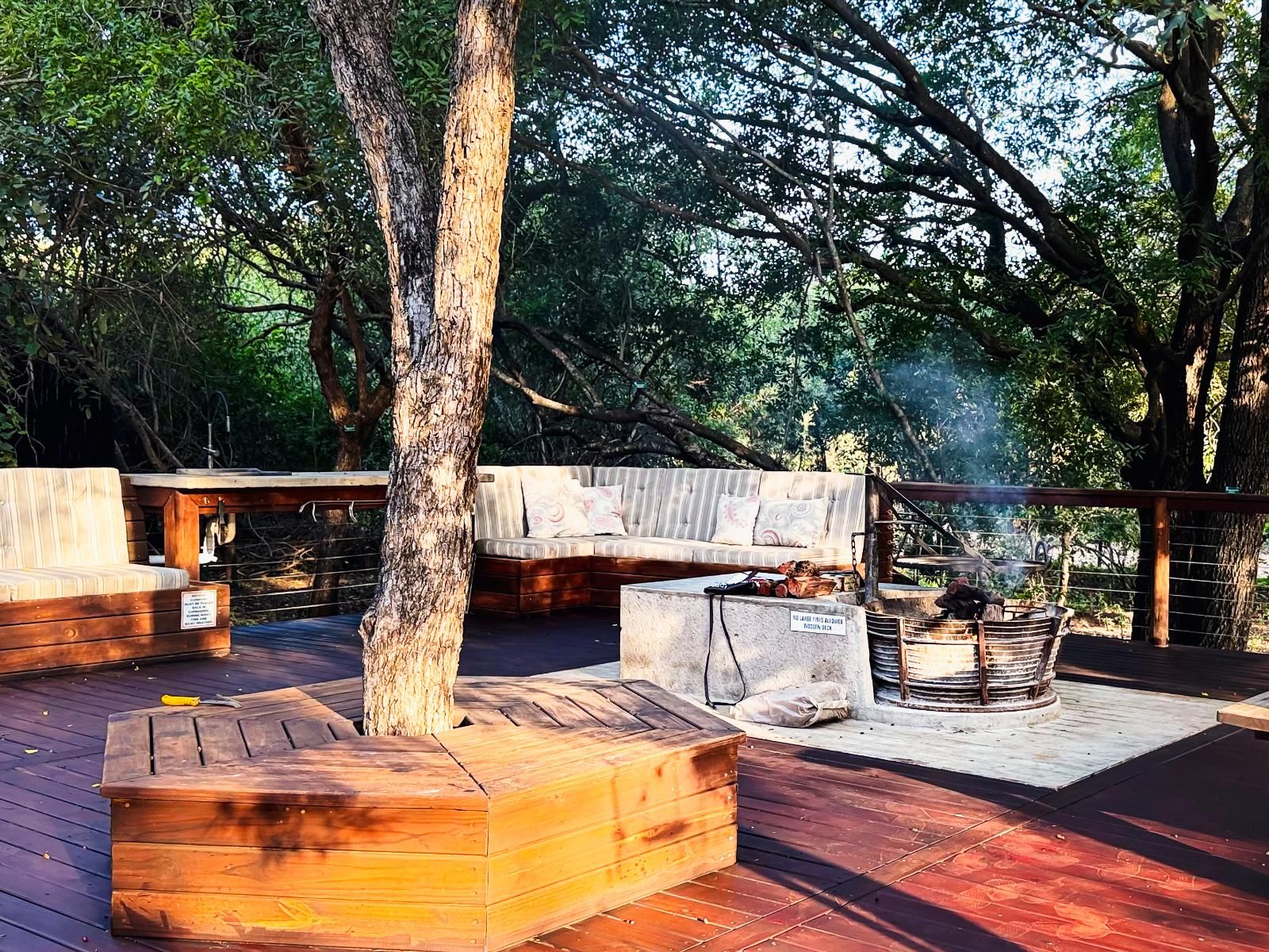 Eine Terrasse im Freien mit Grill, Sitzgelegenheit und einer Holzbank.
