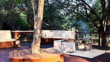 Eine Terrasse im Freien mit Grill, Sitzgelegenheit und einer Holzbank.