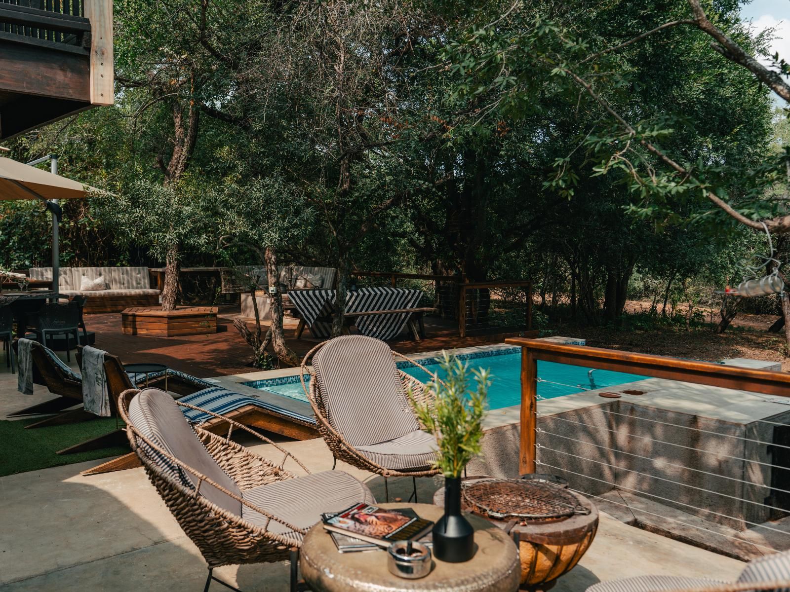 A poolside area with wicker chairs, a table with magazines, and a small plant.