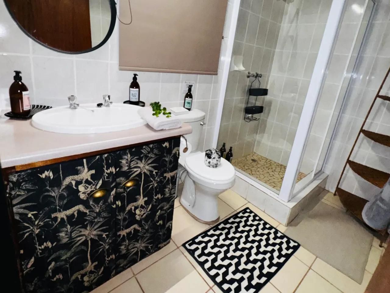 Ein Badezimmer mit weißem Waschbecken, WC und Duschbereich.