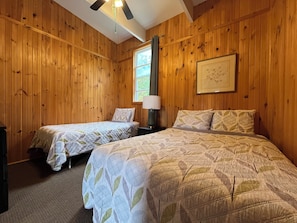 A room with two beds, wooden walls, a ceiling fan, a window, and a framed picture on the wall. - Cozy Chalet #2/ Heated Pool/ Close To Beach/ On Site Activities! (Brackley Beach)