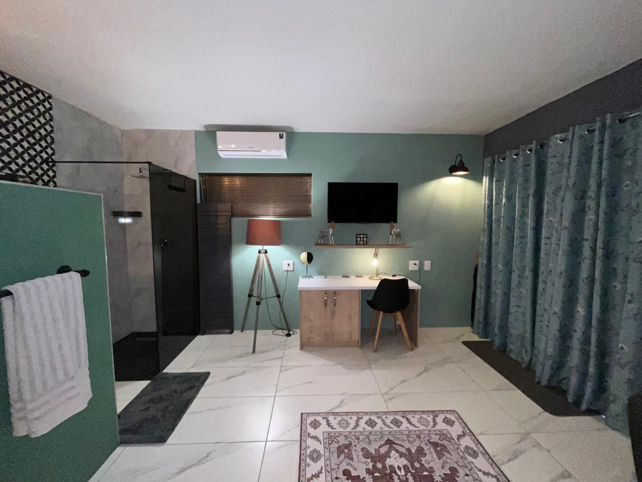 Habitación compacta con escritorio, silla y una pequeña cocina.