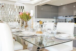 Un espace repas moderne avec une table en verre, des chaises blanches et un élément décoratif central.