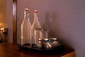 Dos botellas de vidrio con tapas metálicas sobre una bandeja con recipientes de metal.