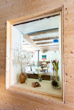 A wooden-framed mirror reflecting a room with a bed, a chair, and a vase with flowers. - Cottage 'Mas Du Cres Gîte' with Private Terrace, Private Garden and Wi-Fi (Galargues)