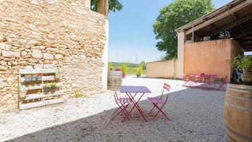 A courtyard with stone walls, a gravel ground, and outdoor furniture.