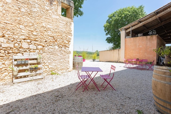 A courtyard with stone walls, a gravel ground, and outdoor furniture.