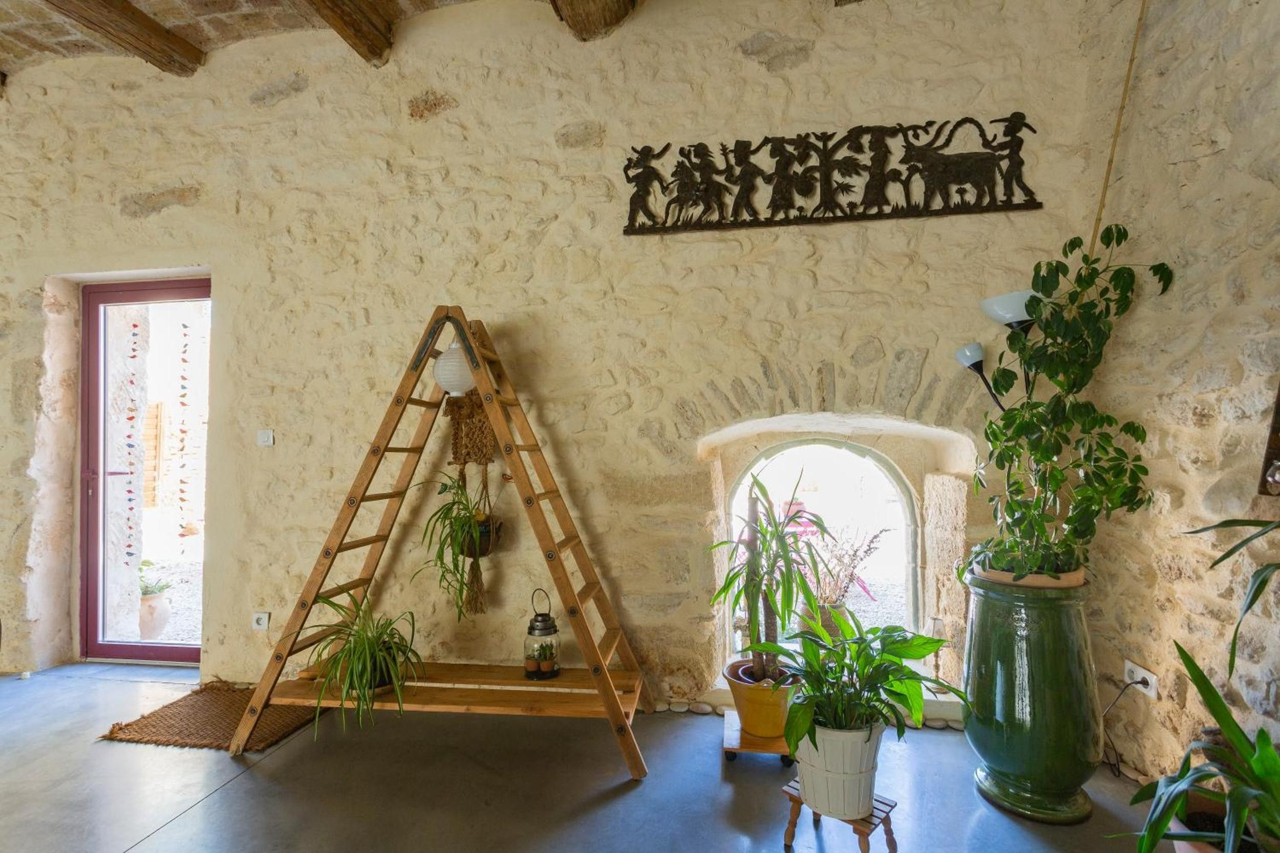 Een rustiek interieur met een houten ladder, plantenpotten en een stenen muur.