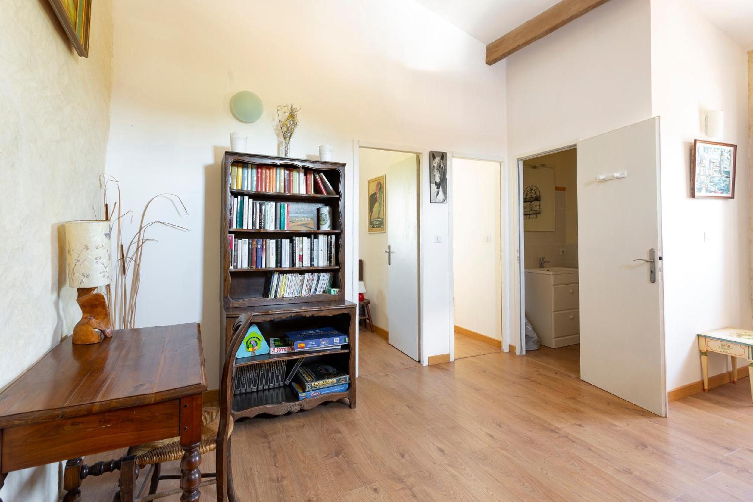 Ein Zimmer mit einem Bücherregal aus Holz, einem Schreibtisch und einer Tür zu einem anderen Raum.