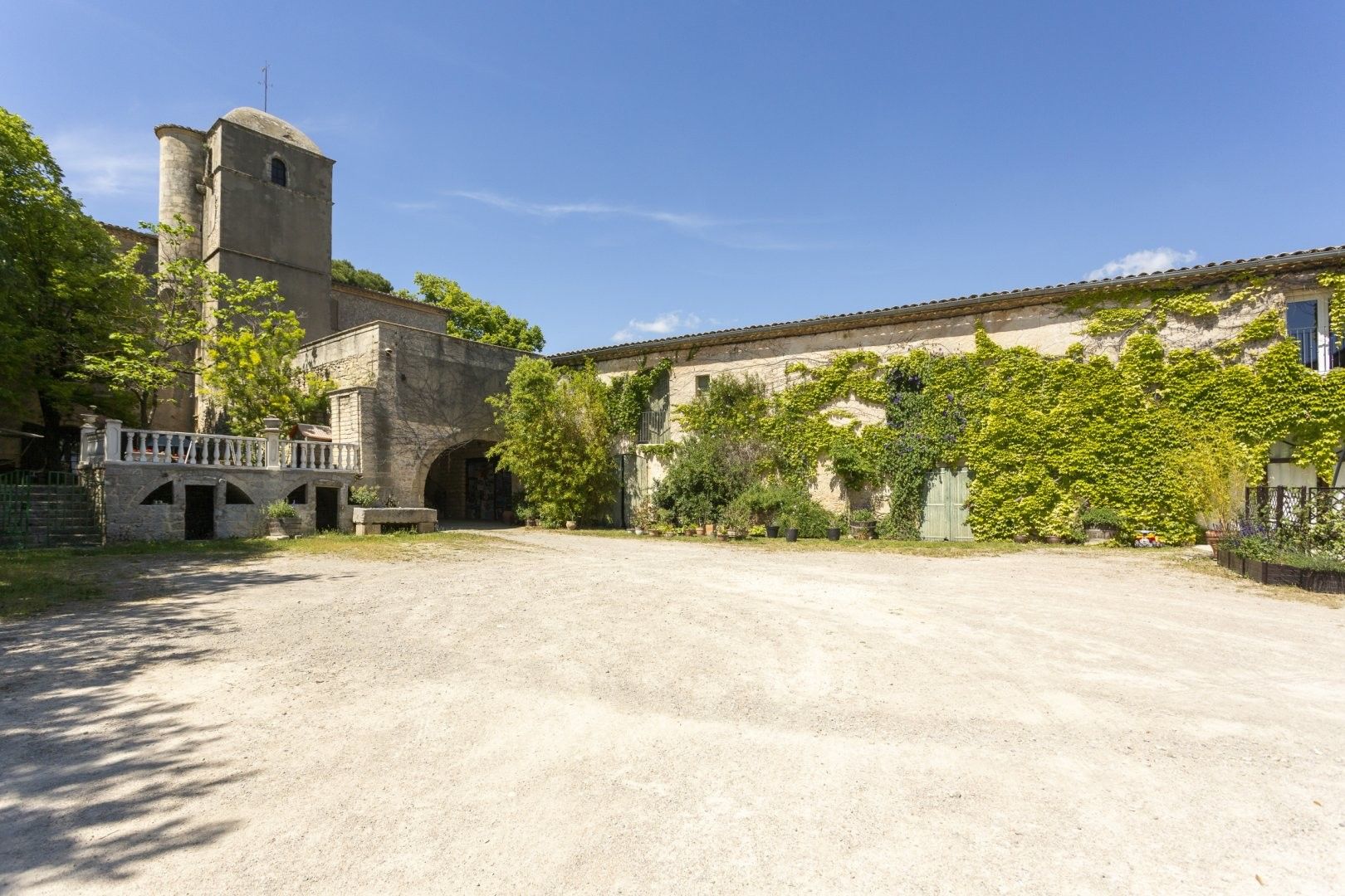 Un cortile con un edificio in pietra, una piccola torre e un porticato.