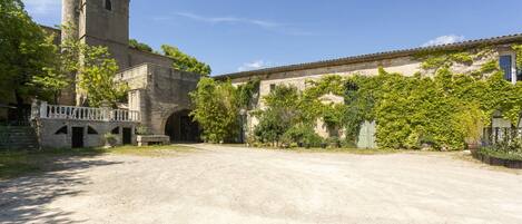 A courtyard with a stone building, a small tower, and a covered walkway.