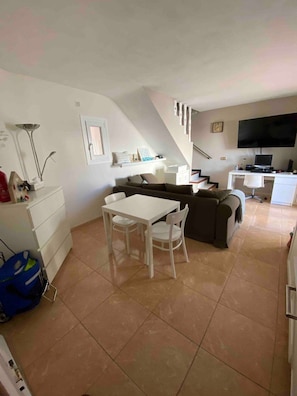Ein kompakter Wohnbereich mit Essbereich, Sofa, Fernseher und Treppe.