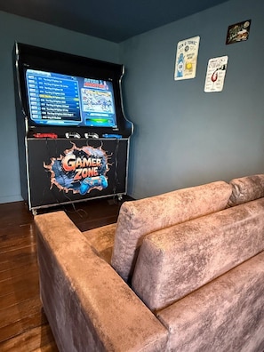 Ein Zimmer mit einer Spielkonsole, einer Couch und Wanddekorationen.