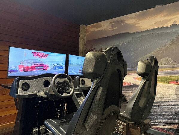 Ein Rennsimulator-Setup mit zwei Bildschirmen, die ein Rennspiel zeigen, einem Lenkrad und einem Rennsitz.