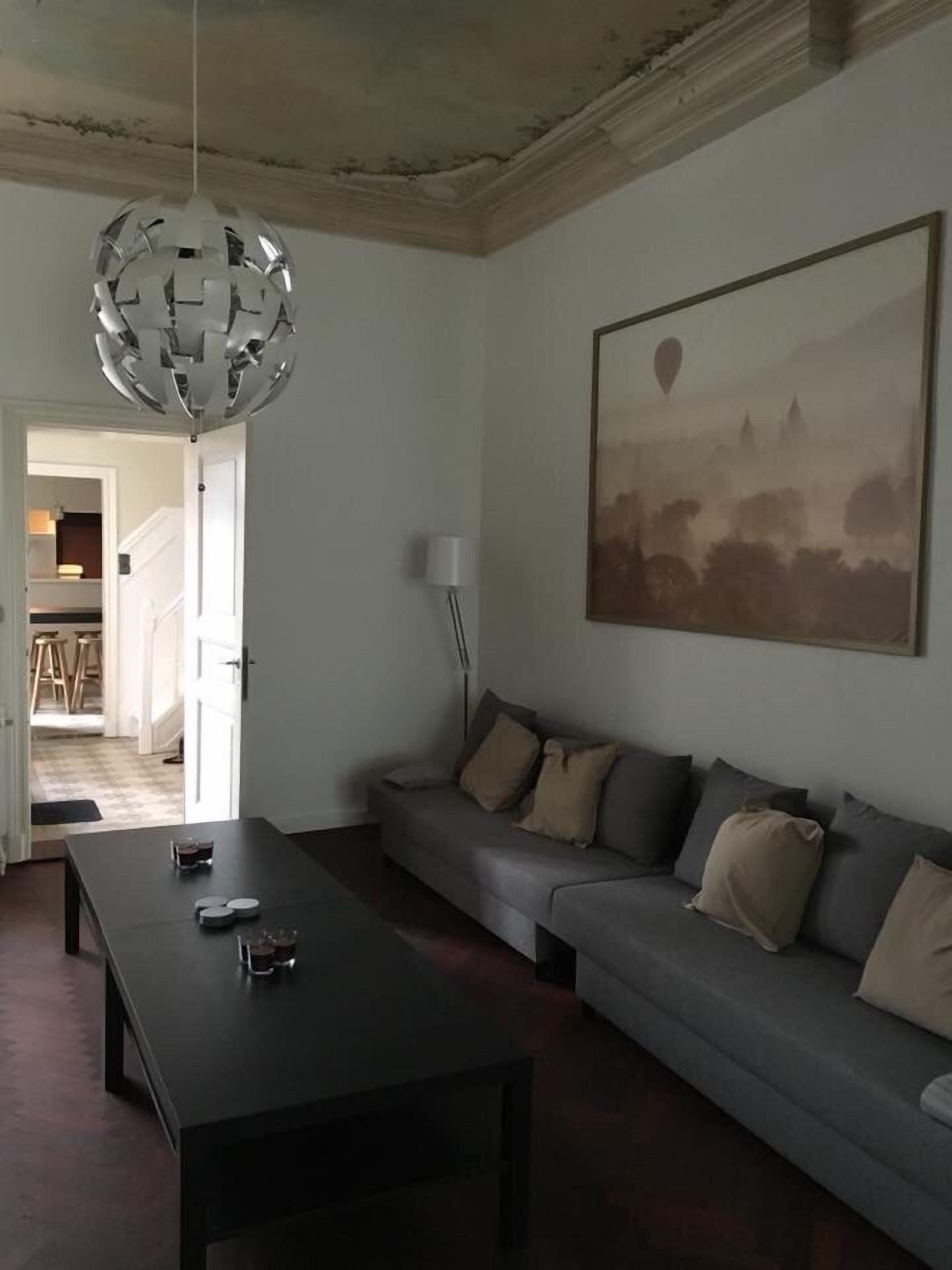 Un salon avec un canapé, une table basse, une suspension et un tableau au mur.
