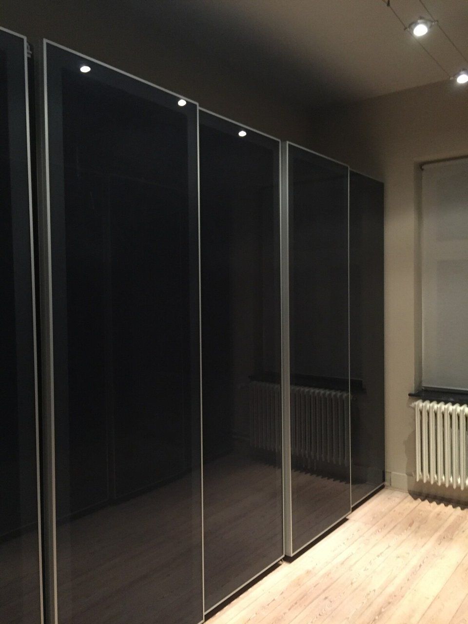 Una habitación con puerta corredera de vidrio, un radiador y suelo de madera.