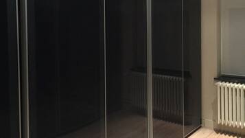 Una habitación con puerta corredera de vidrio, un radiador y suelo de madera.