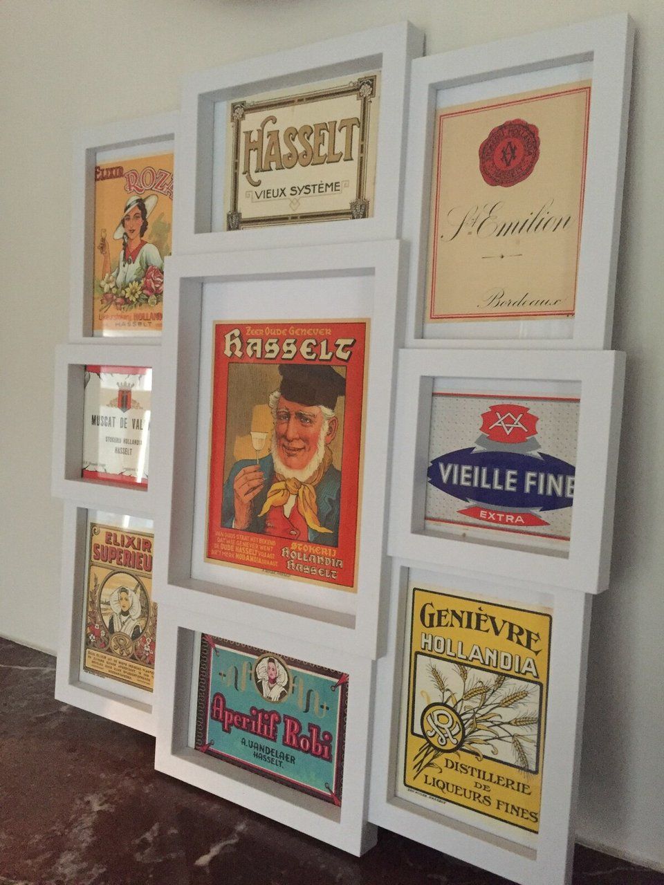 Een muur met meerdere lijstwerken van oude advertenties.