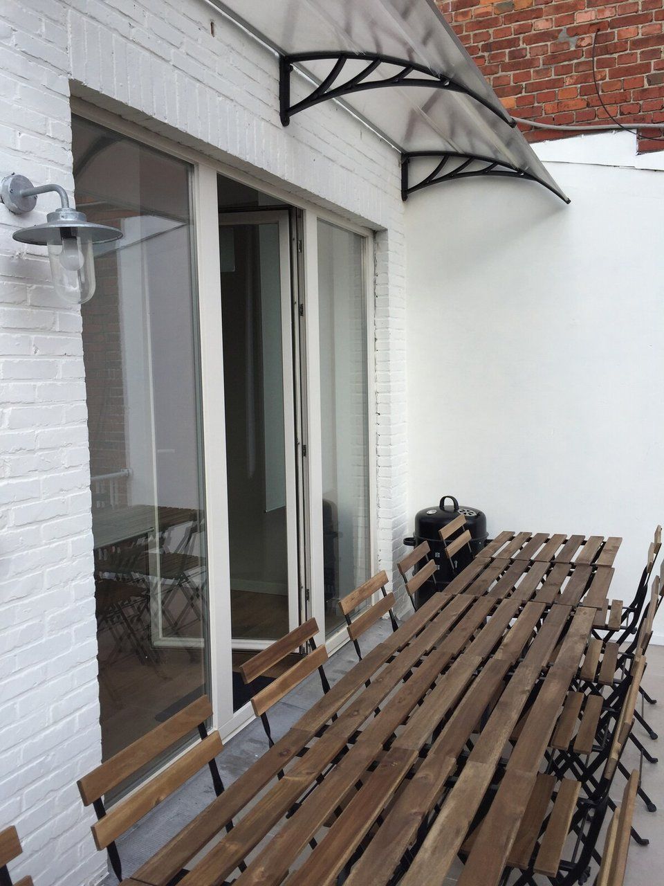 Un'area patio con una panchina di legno e un barbecue.