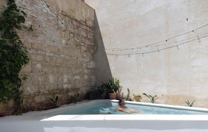 Une piscine avec un mur en briques et des guirlandes lumineuses.