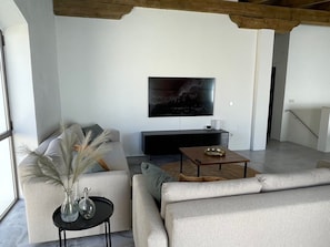 Un salon moderne avec un canapé, une table basse et un téléviseur fixé au mur.