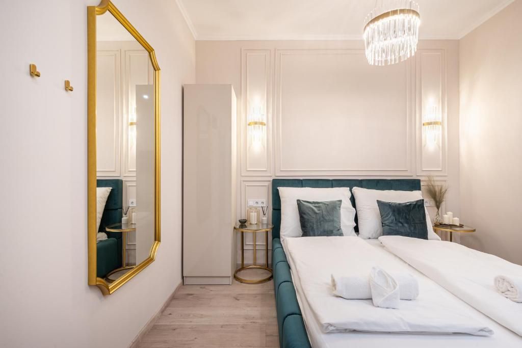 A hotel room with a large bed, a mirror, a chandelier, and a wardrobe.