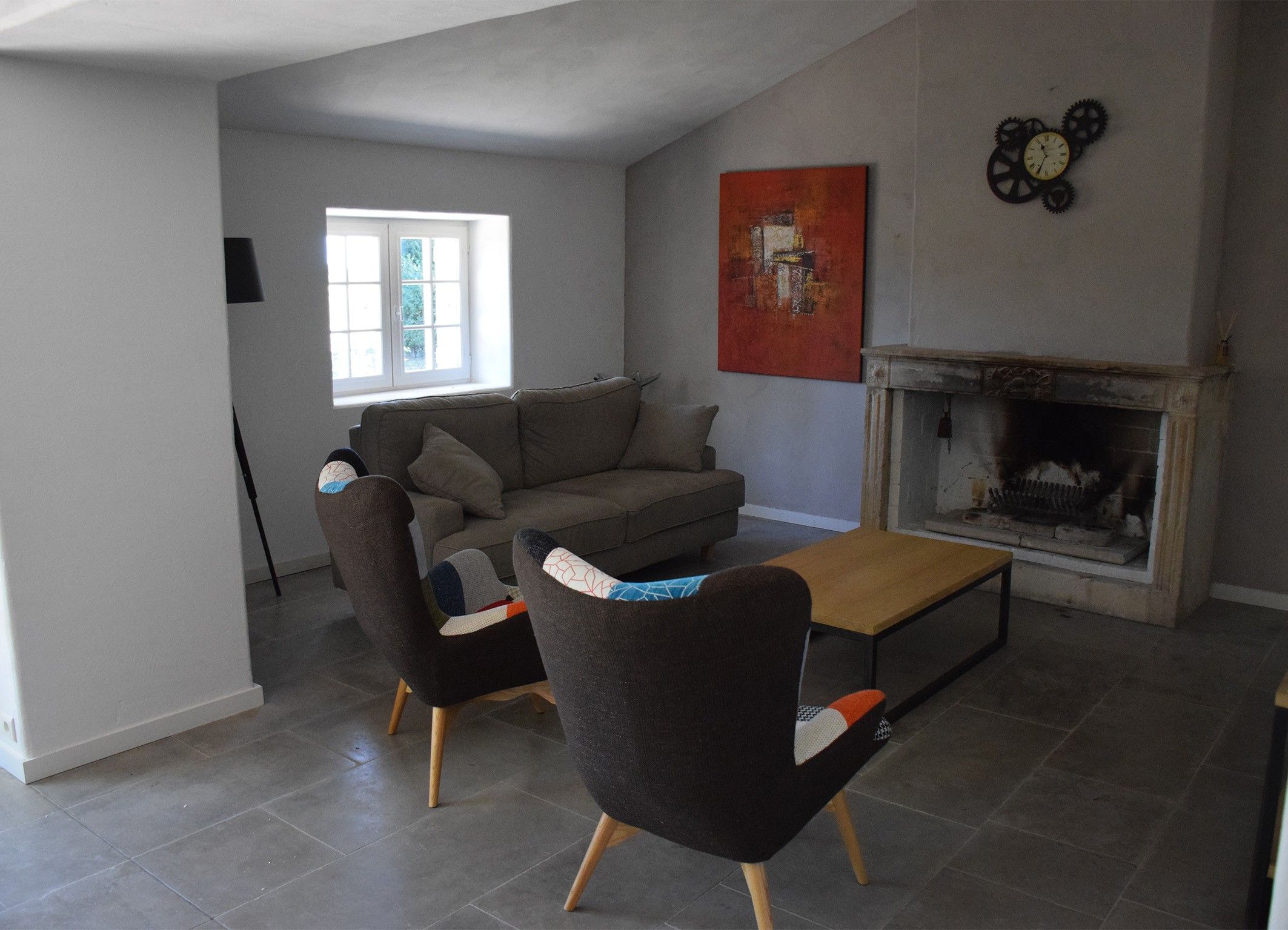 Ein Wohnzimmer mit einer Couch, zwei Sesseln, einem Couchtisch, einem Kamin und einem Fenster.