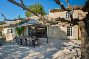 A stone building with a patio area featuring a table and chairs.