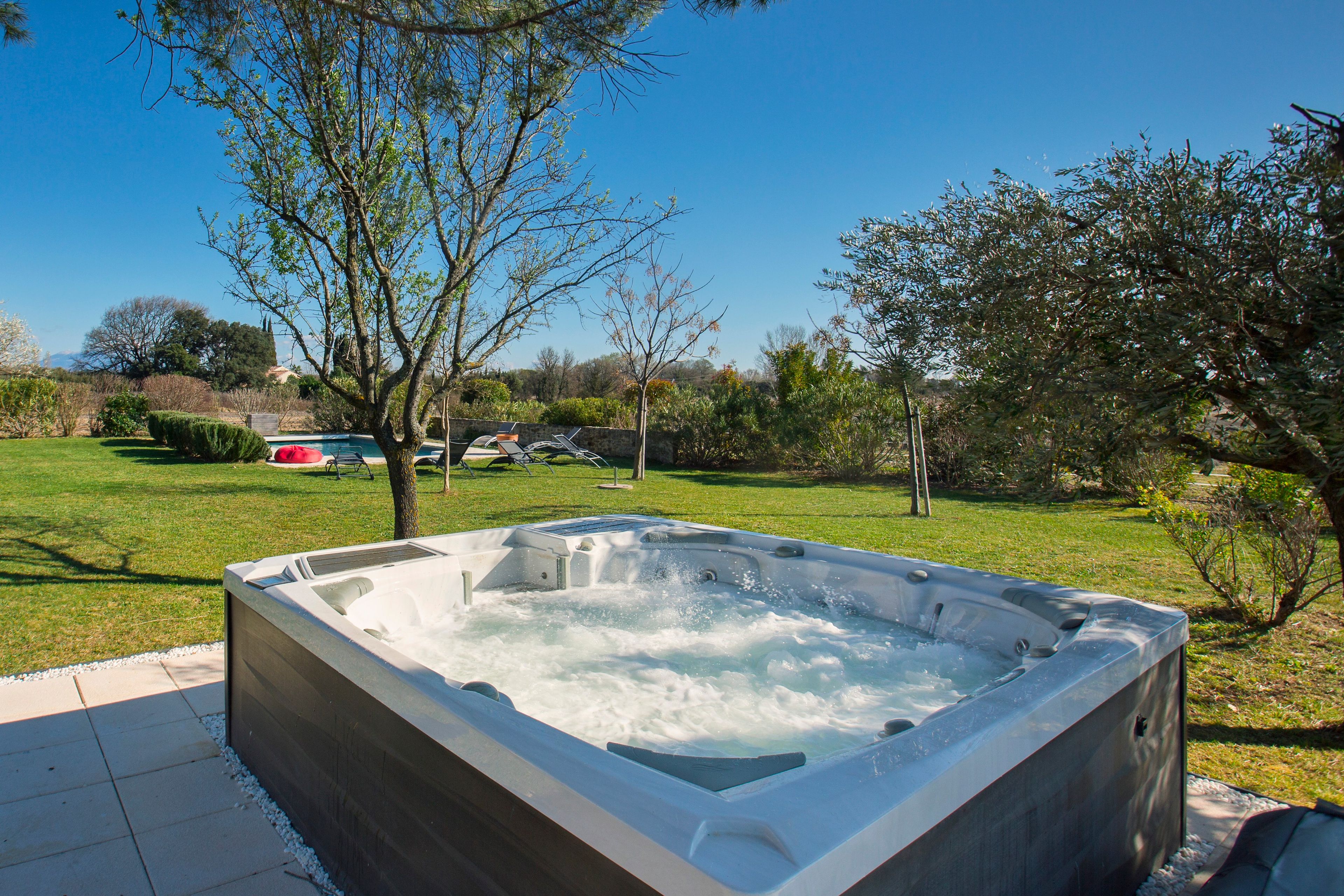 A hot tub in a garden with a clear sky.