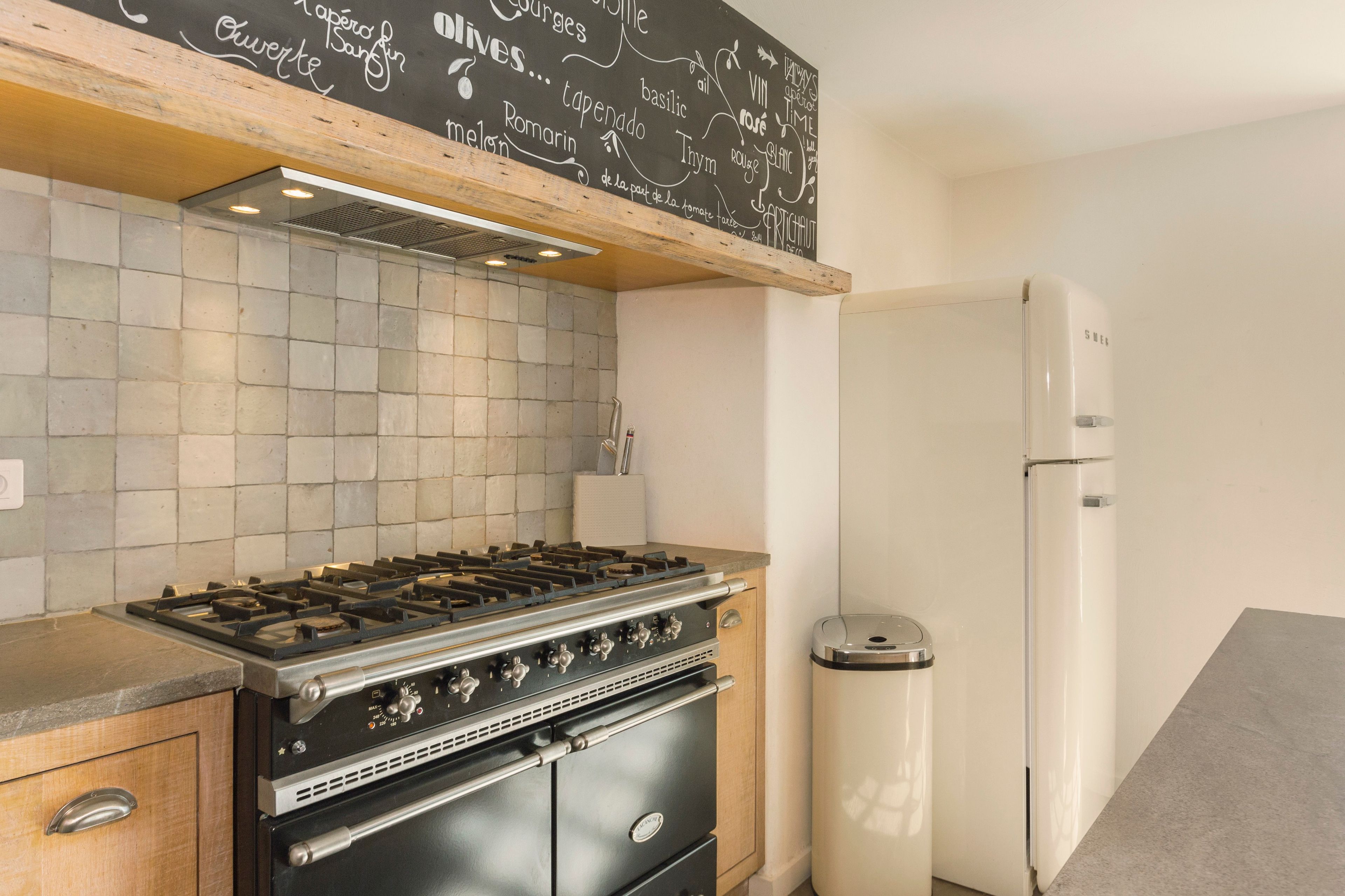 Eine Küche mit Gaskochfeld, Backofen und einem weißen Kühlschrank.