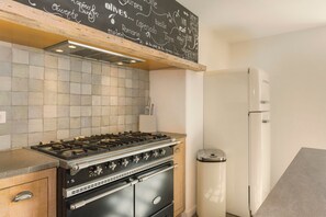 Eine Küche mit Gaskochfeld, Backofen und einem weißen Kühlschrank.