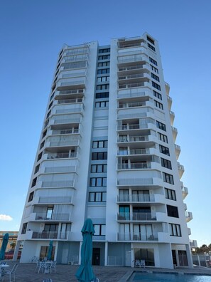 Ein mehrstöckiges Hotel mit Balkonen, einem Schwimmbad und Außenbereich-Sitzgelegenheiten.