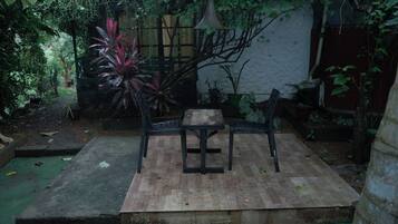Een buitenzitplaats met een tafel en stoelen, omgeven door planten en een houten terras.