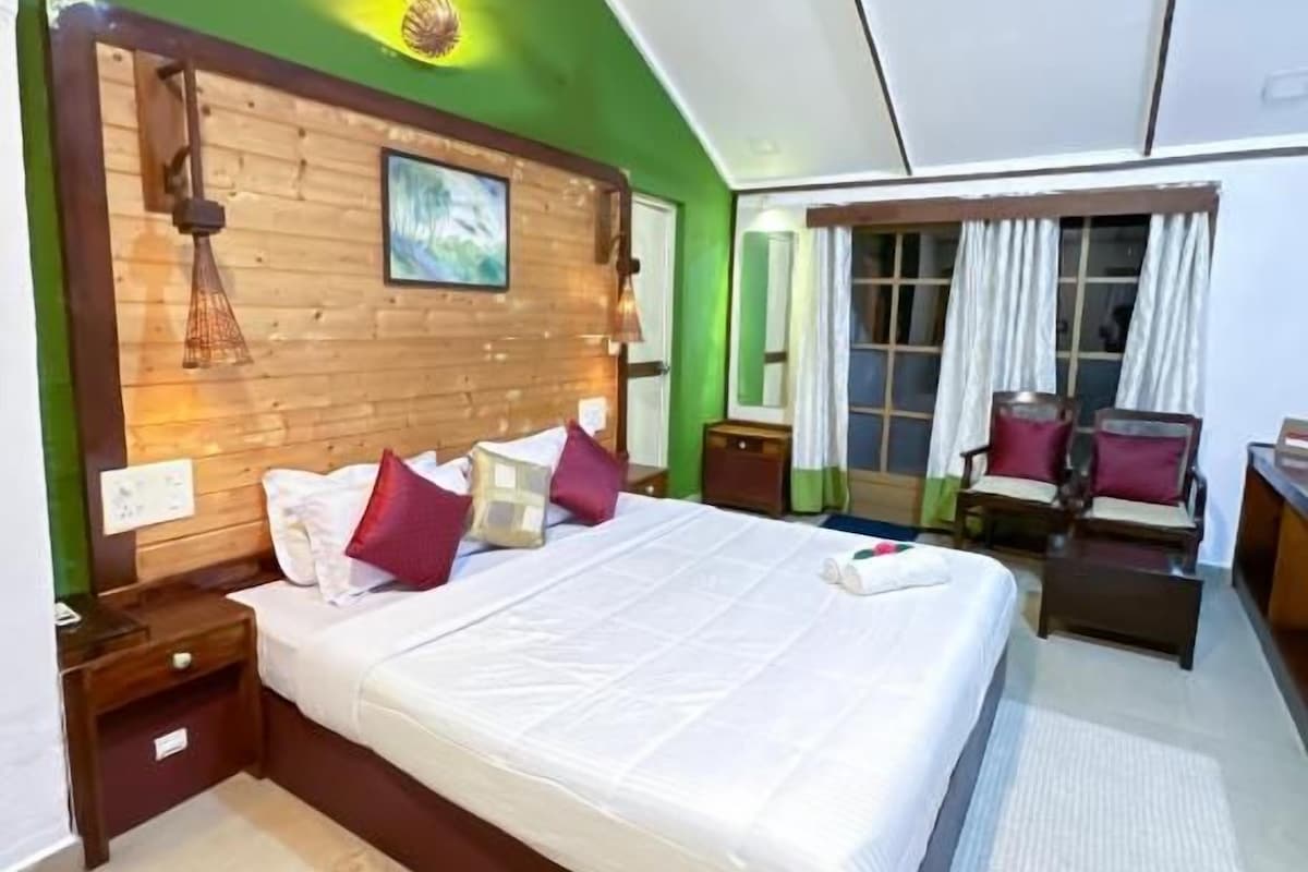 A bedroom with a large bed, wooden headboard, bedside tables, a ceiling fan, and a view of the outside.