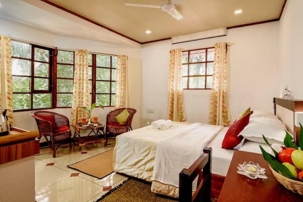 A hotel room with a bed, a sitting area with chairs, a small table, and a window with curtains.