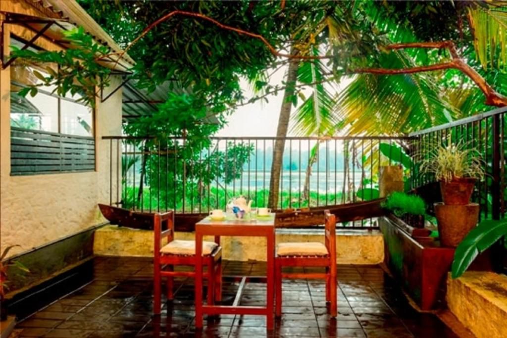 A covered outdoor seating area with a table and chairs, surrounded by lush greenery and a view of the landscape.