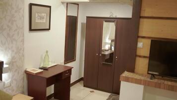 Een kamer met een houten garderobe, een bureau, een spiegel en een televisie.