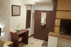 A room with a wooden wardrobe, a desk, a mirror, and a television. - Riverdale Homestay Kumarakom by LexStays (Arpookara)