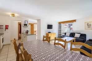 Un espace de vie compact comprenant un coin repas, une kitchenette et un ensemble de canapés.