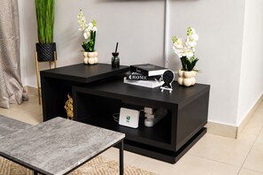 Ein modernes Wohnzimmer mit einer schwarzen Unterhaltungsecke, einem kleinen Tisch und Zierpflanzen.