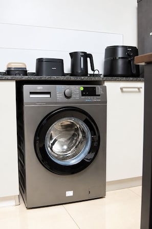 Máquina de lavar compacta e moderna, com visor digital, localizada em cozinha com bancada de granito.