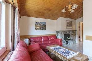 Ein Wohnzimmer mit einem roten Ledersofa, einem Kamin und einem Gemälde an der Wand.