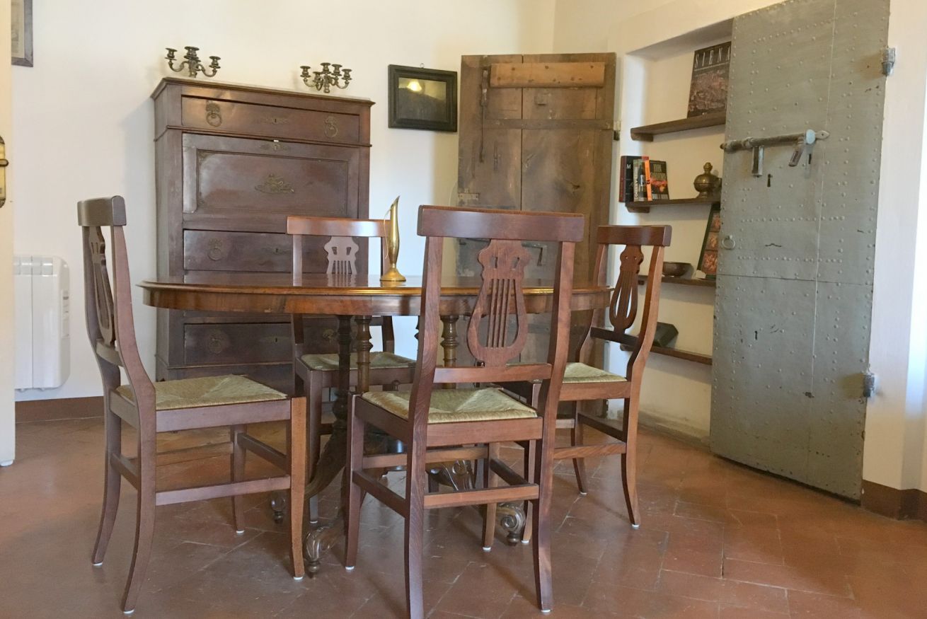 Un'area pranzo con un tavolo e sedie in legno, un armadietto e un'ampia porta metallica.