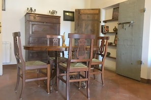 Un'area pranzo con un tavolo e sedie in legno, un armadietto e un'ampia porta metallica.