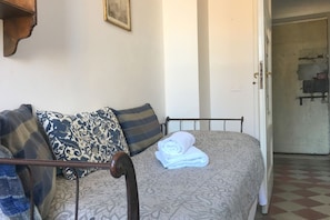 Un letto con una coperta fantasia, un asciugamano arrotolato e diversi cuscini.