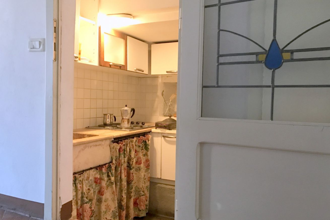 Una cucina con mobili bianchi, un fornello e un bollitore.