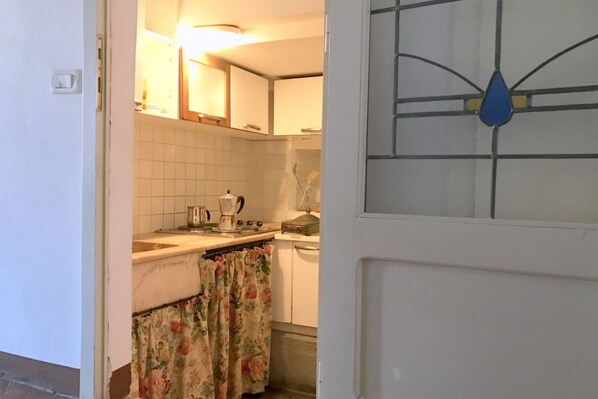 A kitchen with white cabinets, a stove, and a kettle. - Fonte Gaia Apartment (Siena)